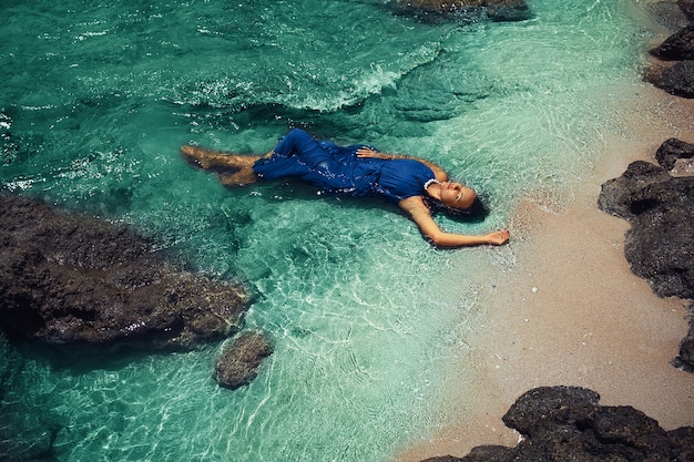 Beautiful woman in blue dress posing in the sea