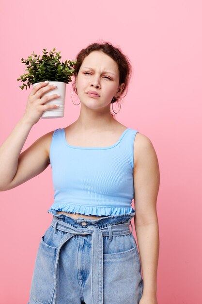 青いTシャツとショートパンツの美しい女性は、植木鉢のピンクの背景を変更せずに