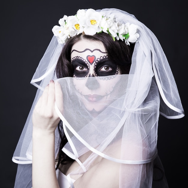 Photo beautiful woman bride with creative sugar skull make up and bridal veil over black background