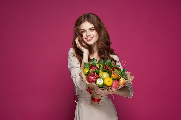 Красивая женщина яркий макияж привлекательный взгляд букет фруктов розовый фон