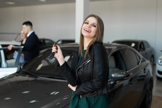 Beautiful woman or car salesman stand holding a new car remote key in a car showroom