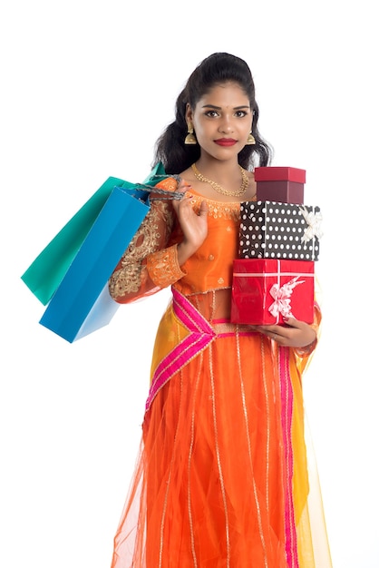 Beautiful woman carrying many shopping bags and gift Box on white.