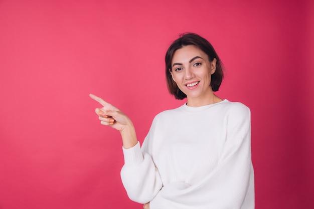 Beautiful woman in casual white sweater on red wall