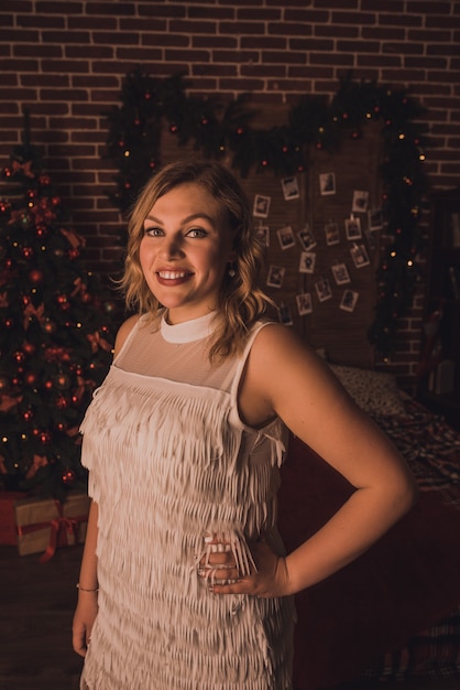 Beautiful woman celebrating New Year and Christmas at decorated Christmas tree and garlands