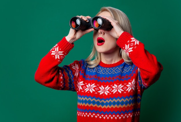 Beautiful woman in Christmas sweater with binoculars  