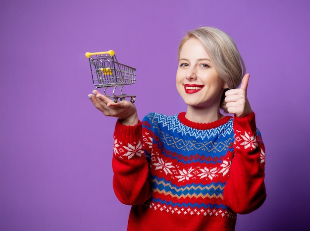 Beautiful woman in christmas sweater with shopping cart