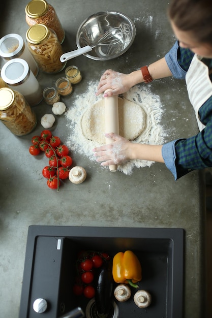 Foto bella donna che cucina la torta in cucina in piedi vicino alla scrivania