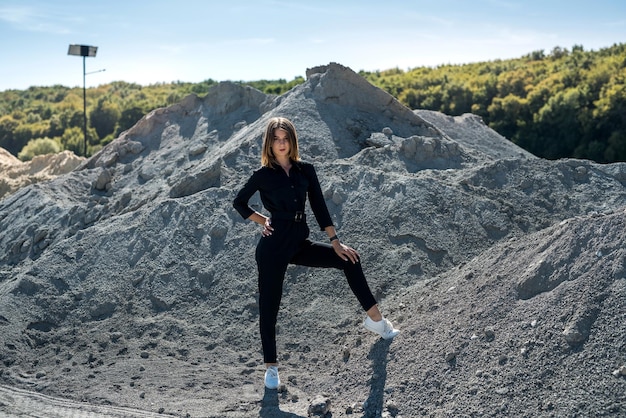 Beautiful woman in coveralls posing for the camera in the sand quarry summertime