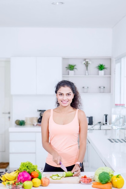 Beautiful woman cutting vegetables in kitchen