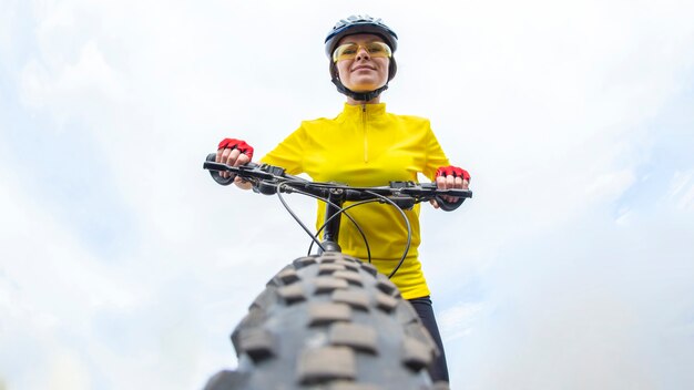 Beautiful woman cyclist looking forward to the wheel of the bike