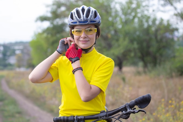 自然の中で自転車を持っている美しい女性サイクリスト。健康的なライフスタイルとスポーツ。レジャーと趣味