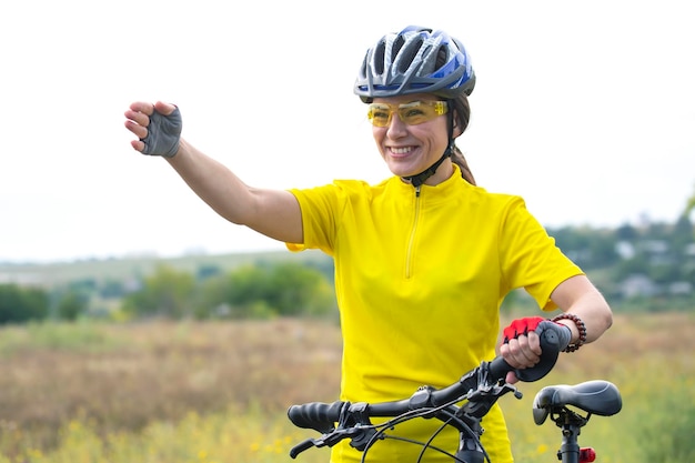 Beautiful woman cyclist in yellow points her hand forward