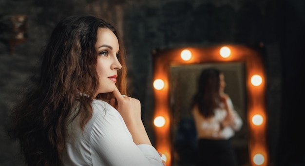 Beautiful woman in a dark studio in a white shirt posing at the camera