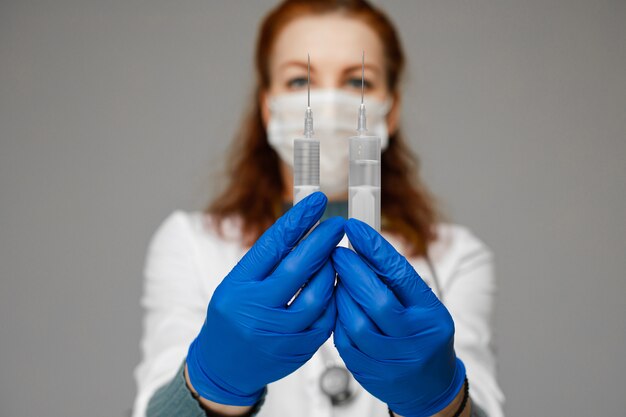 Красивая женщина-врач в белой медицинской одежде, маске, синие перчатки и фонендоскоп на ее плечах, фотография изолированы