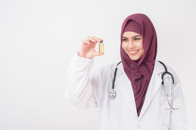 Beautiful woman doctor with hijab is holding vaccine  on white background