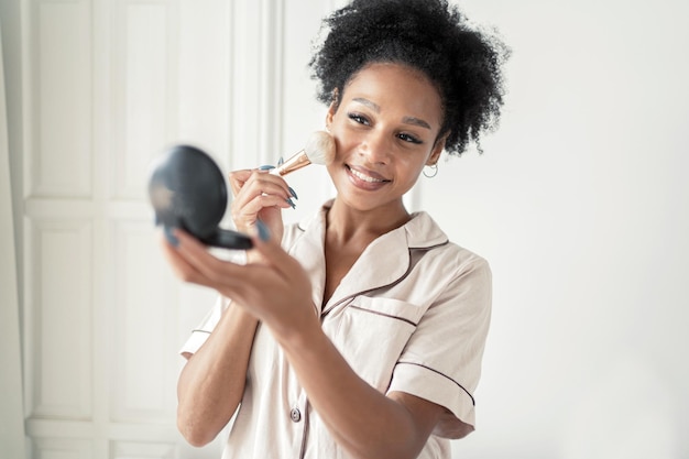 Bella donna che fa il rullo di massaggio facciale applicare cosmetici sulla pelle per il ringiovanimento