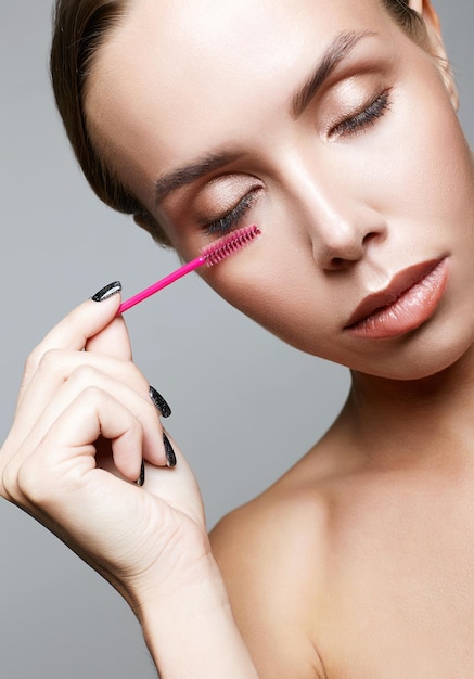 Beautiful woman doing makeup applies mascara