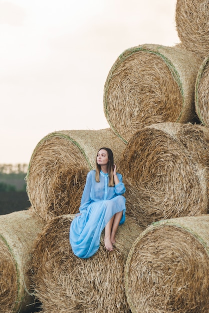 Beautiful woman in a dress on haystacks. 