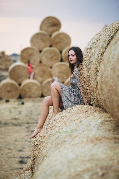 Beautiful woman in a dress on haystacks. 