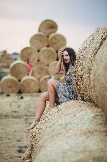 Beautiful woman in a dress on haystacks. 