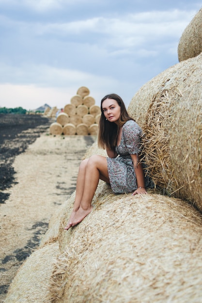 Beautiful woman in a dress on haystacks. 