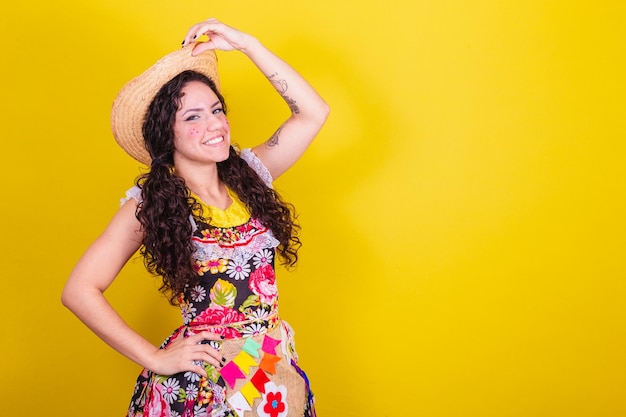 Beautiful woman dressed in typical clothes for a festa junina holding the hat