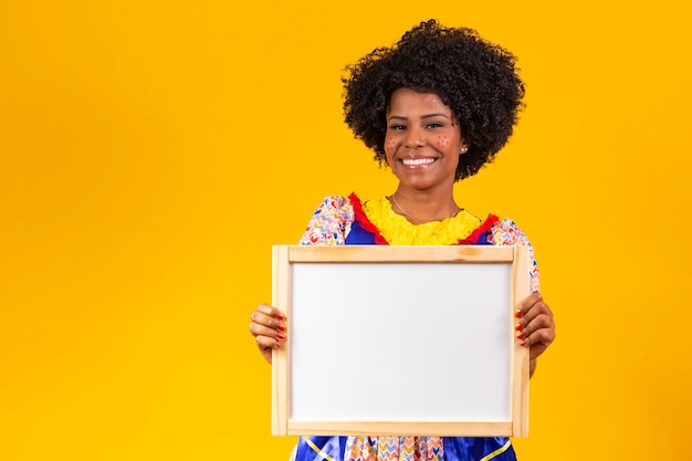 Beautiful woman dressed in typical clothes for a Festa Junina holding sign for text or ad