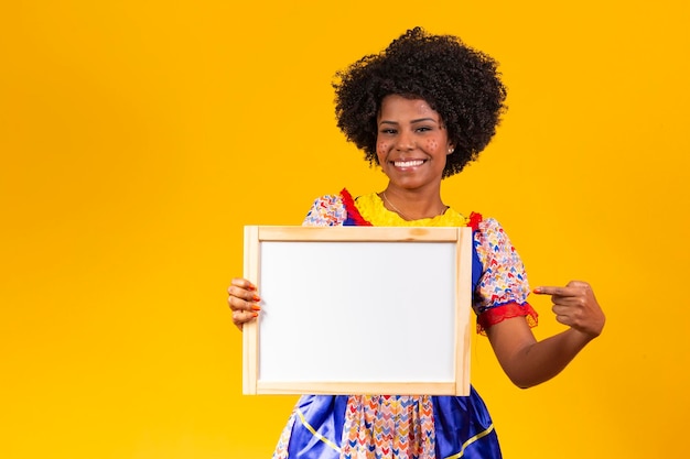 Beautiful woman dressed in typical clothes for a Festa Junina holding sign for text or ad