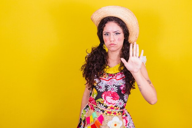 Beautiful woman dressed in typical clothes for a Festa Junina palm indicating stop no