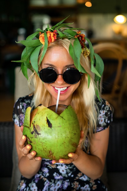 Foto noce di cocco bevente della bella donna nel caffè tropicale