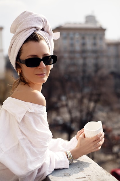 Красивая женщина пьет кофе на балконе