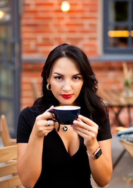 Beautiful woman drinking coffee in a cafe and eating croissant