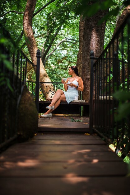 Beautiful woman drinking coffee in a treehouse cafe.