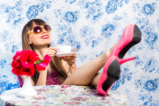 Beautiful woman drinking hot tea over blue floral background