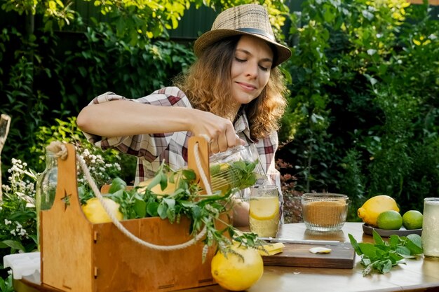 Beautiful woman drinking lemonade cocktail relaxing in summer garden