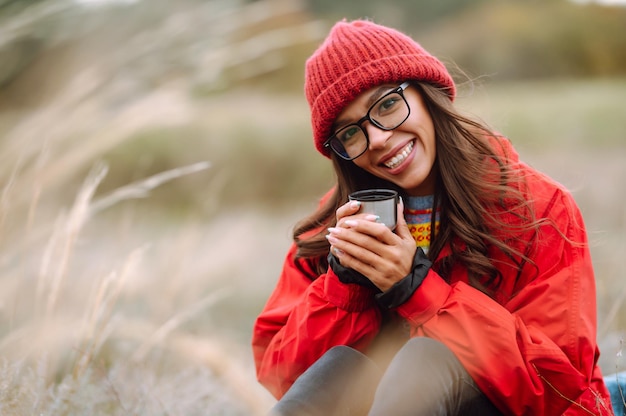 Beautiful woman drinking tea from thermos on cold autumn day Rest relaxation lifestyle concept