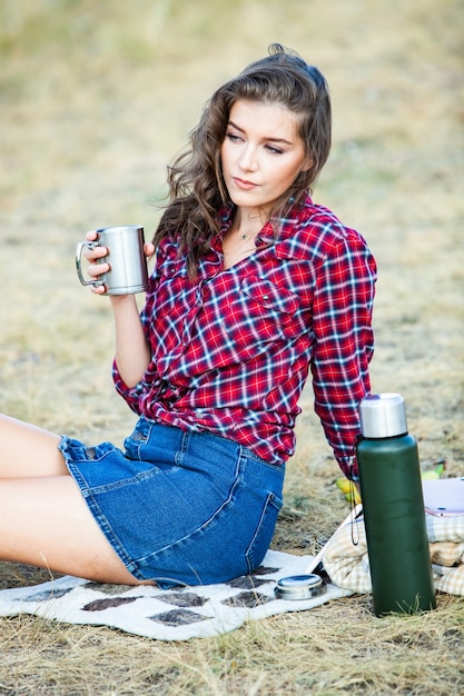 Beautiful woman drinks tea outdoors. Hipster woman relaxing in nature