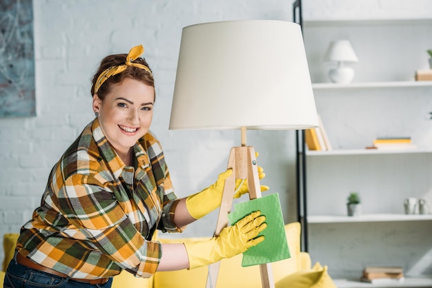 Фото Красивая женщина пылить лампу с тряпкой дома