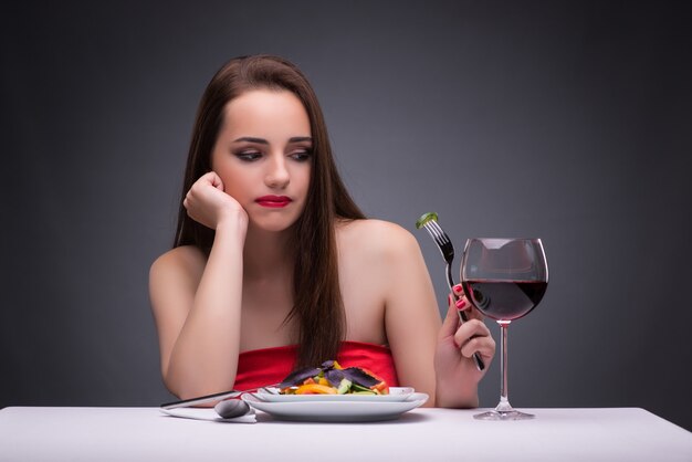 Foto bella donna che mangia da solo con il vino