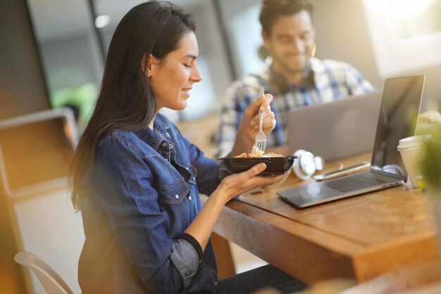 Beautiful woman eating lunch whilst working in co working space