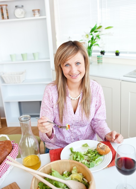 Beautiful woman eating salad in the kitchen