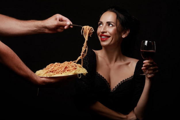 美しい女性がスパゲッティを食べ、ワインを飲む