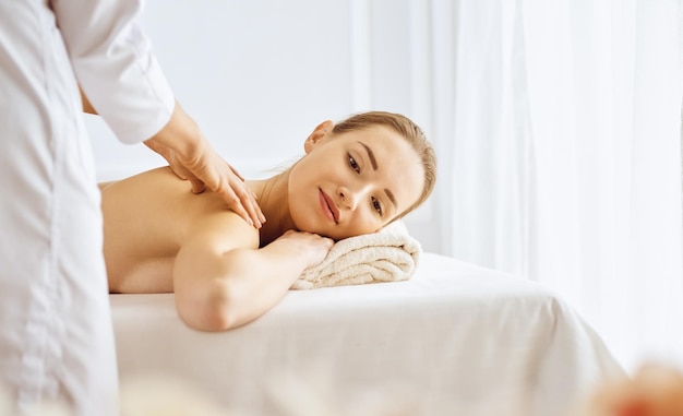 Beautiful woman enjoying back massage with closed eyes. Spa treatment concept.