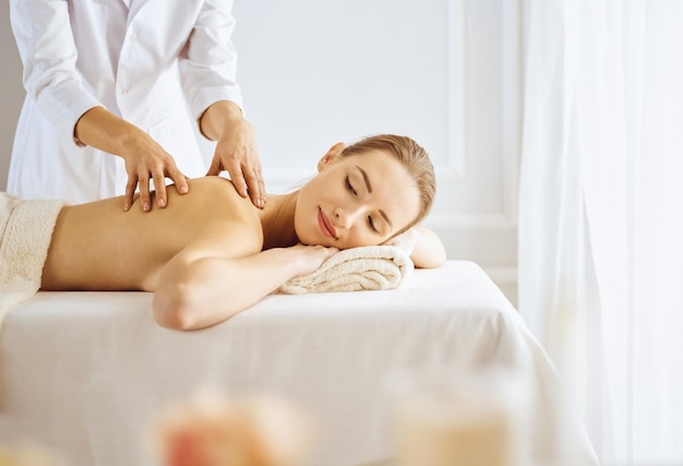 Beautiful woman enjoying back massage with closed eyes. Spa treatment concept.