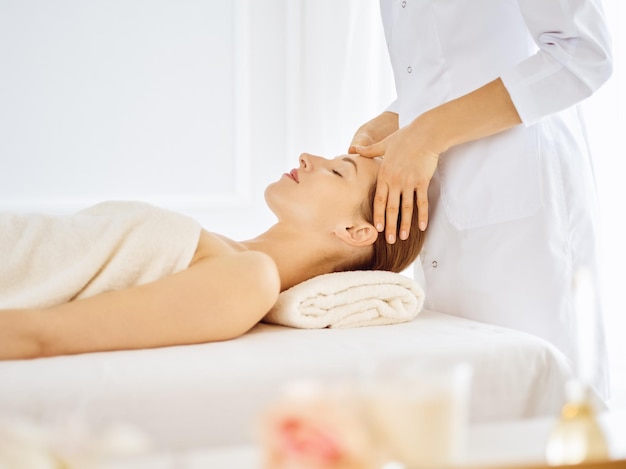 beautiful woman enjoying facial massage with closed eyes in spa center. relaxing treatment concept in medicine.