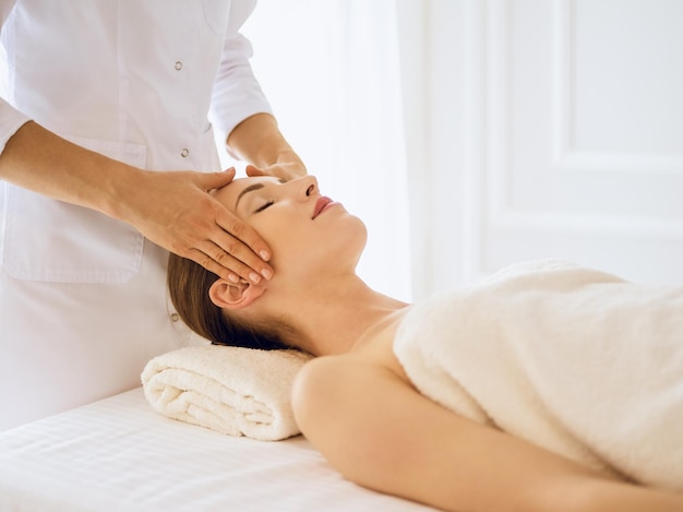 Beautiful woman enjoying facial massage with closed eyes. Spa treatment concept in medicine.