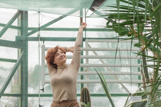 緑の植物の中に立って楽しんでいる美しい女性