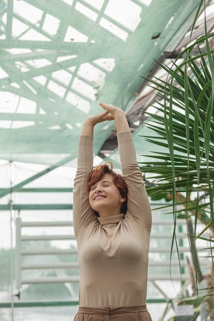 緑の植物の中に立って楽しんでいる美しい女性