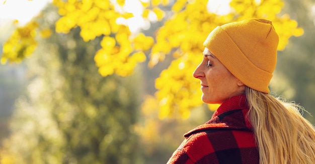 Photo beautiful woman enjoying sunny autumn day in nature standing in the park at the city with colorful leaves on a tree and relaxing taking a breath of fresh air with copyspace for individual text