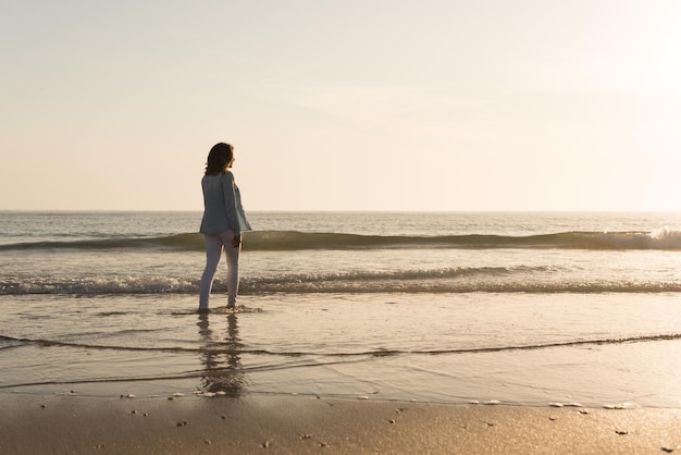 Bella donna che gode del tramonto sulla spiaggia